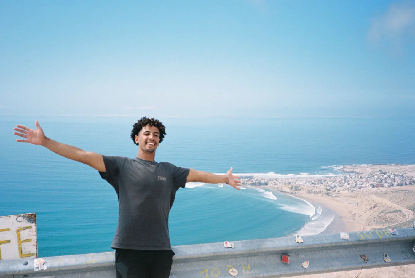 Amine, les bras ouverts face à la baie sur la côte marocaine
